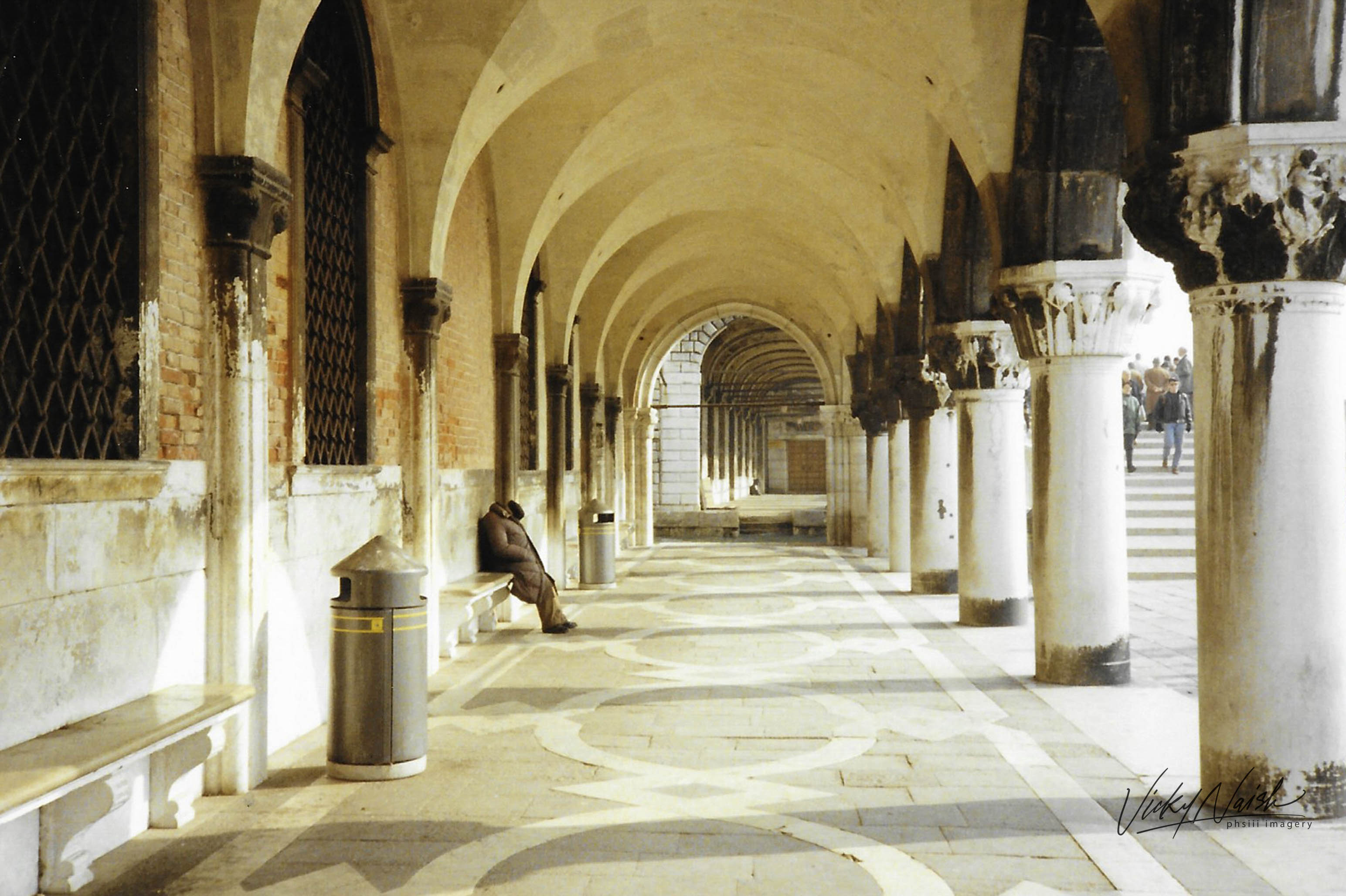 a stone Italian archway with a man resting on a stone bench 