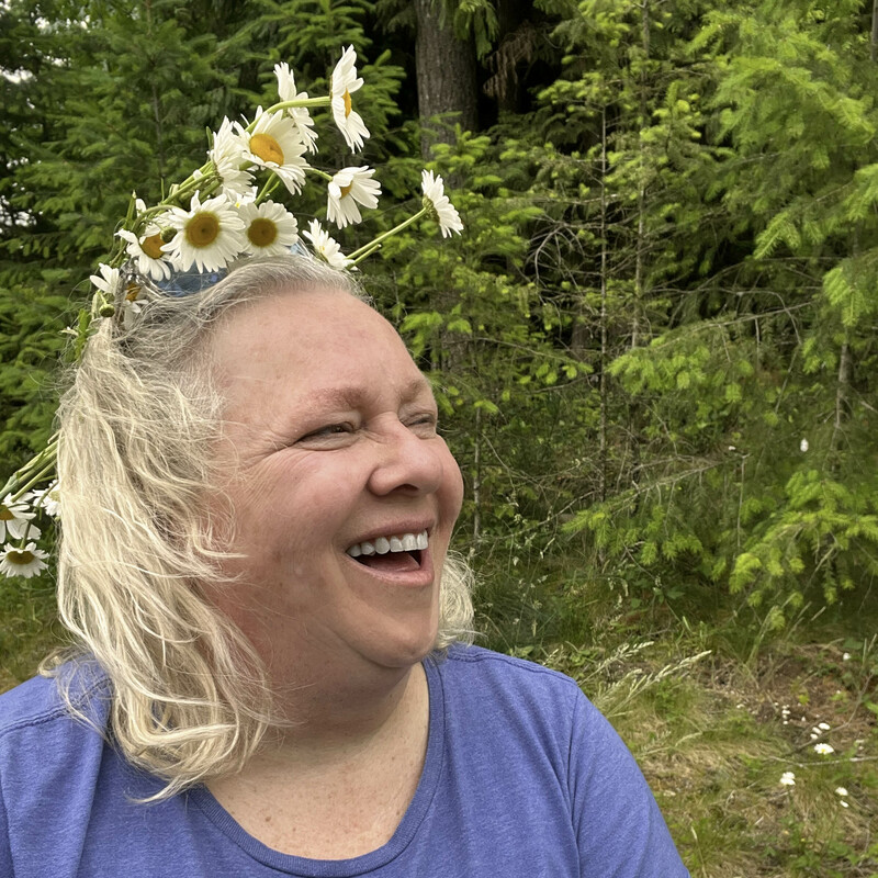 selfie of laughing woman with a haphazard crown of fresh picked  daisies