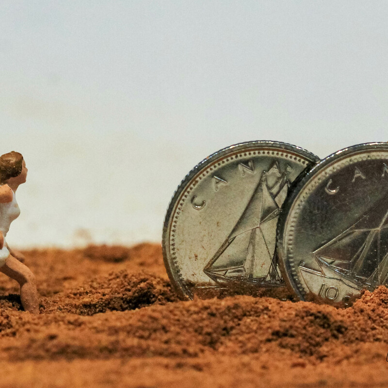 miniature diorama of woman chasing rolling coins through deep dirt